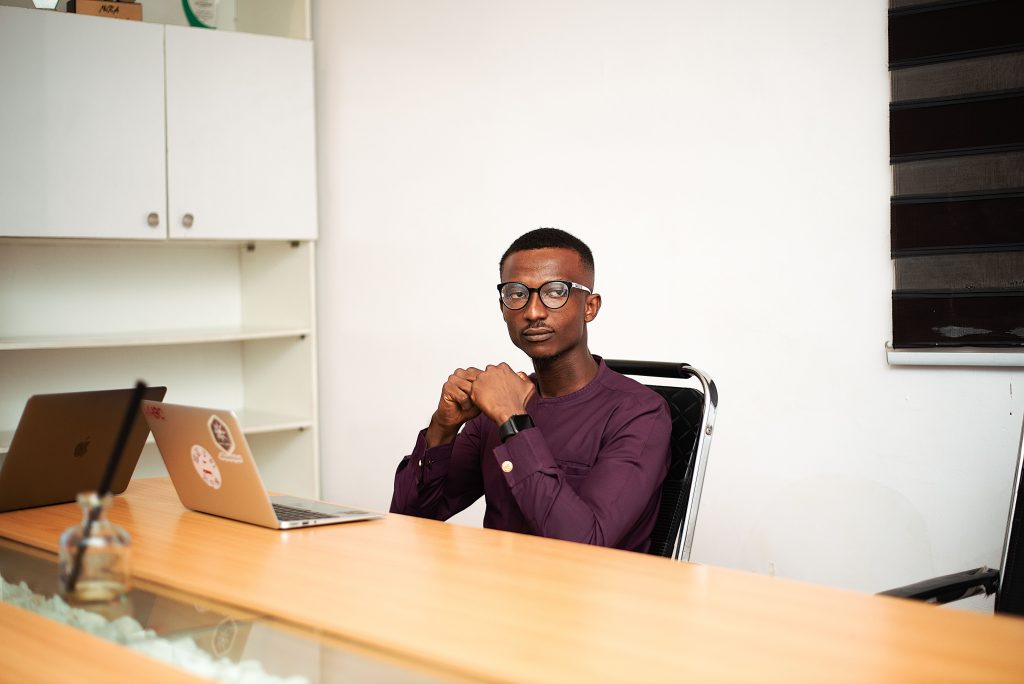 Business professional sitting at a desk in an office environment, working on a laptop with focused intent.