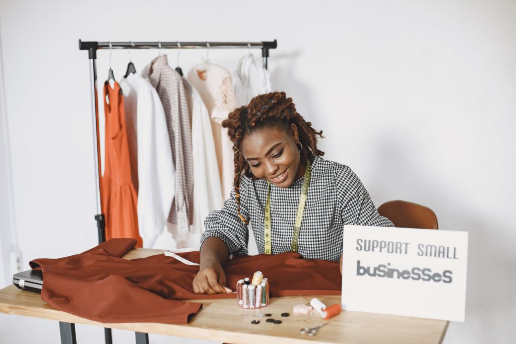 A fashion designer working on garments at her sewing studio, supporting small businesses.
